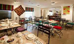 En café med opdækkede borde og stole med farverige puder. (AI-genereret tekst)