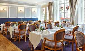 Indendørs billede af en spisesal med opstillede borde og stole. (AI-genereret tekst)