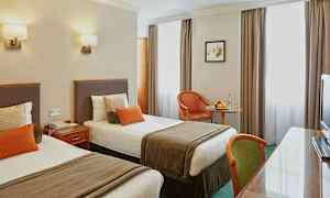 Hotelværelse med to enkeltsenge og bord. (AI-genereret tekst)