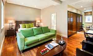 Et hotelværelse med grønne møbler, en stor seng, et træbord og spejle. (AI-genereret tekst)