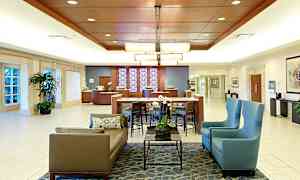 Hotellobby med siddeområder, borde, planter og receptionsdisk. (AI-genereret tekst)