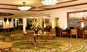 En elegant hotellobby med dekorative tæpper, en central blomsteropsats og komfortable siddepladser. (AI-genereret tekst)