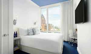 Billede af et hotelværelse med en behagelig dobbeltseng, et stort vindue og moderne indretning. (AI-genereret tekst)