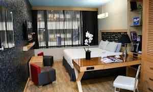 Et moderne hotelværelse med en dobbeltseng, skrivebord og siddeområde. (AI-genereret tekst)