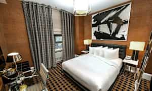 Hotelværelse med moderne indretning, en stor seng, skrivebord og abstrakt kunst på væggen. (AI-genereret tekst)