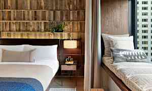 Et moderne soveværelse med en seng, en vinduesbænk med puder og en natbordslampe. (AI-genereret tekst)