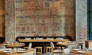 Et rum med murstensvægge og træborde, arrangeret til restaurantbrug. (AI-genereret tekst)