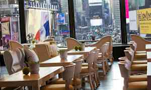 Restaurant med træborde og stole med udsigt over byens neonbelyste skærme. (AI-genereret tekst)