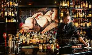 En bar fyldt med flasker med spiritus og tilbehør, med et maleri af en figur i baggrunden. (AI-genereret tekst)