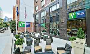 En udendørsterrasse foran et hotel med siddegrupper og planteudsmykning. (AI-genereret tekst)