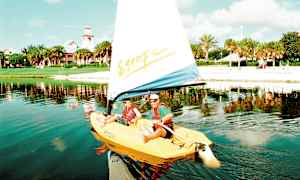 En sejlbåd på en sø med en strand og grønne træer i baggrunden. (AI-genereret tekst)