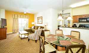 Billede af en rummelig stue og spiseområde med sofa, lænestol, spisebord og tekøkken. (AI-genereret tekst)