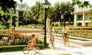 Folk cykler langs en sti ved siden af en smuk springvand i en park. (AI-genereret tekst)