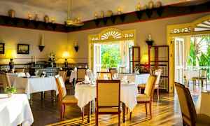 Interiør af en elegant restaurant med borde dækket med hvide duge, træstole og dekorative elementer på væggene. (AI-genereret tekst)