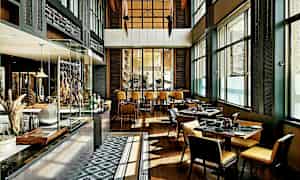 Interiør af en moderne restaurant med borde og stole, store vinduer og et åbent køkkenområde. (AI-genereret tekst)