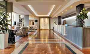 Hotellets lobby med marmorgulv, reception og siddeområde. (AI-genereret tekst)