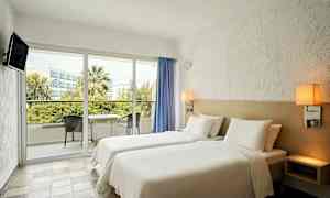 Hotelværelse med to enkeltsenge og en balkon med møbler. (AI-genereret tekst)