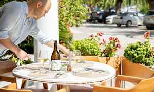 Et opdækket udendørs bord med spiseplads og dekorationer. (AI-genereret tekst)