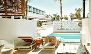 Liggestole ved en swimmingpool med moderne arkitektur i baggrunden. (AI-genereret tekst)