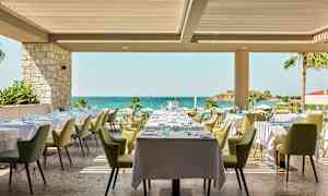 Restaurant med dækkede borde og udsigt til havet. (AI-genereret tekst)