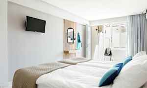 Hotelværelse med senge, tv på væggen og et spejl. (AI-genereret tekst)