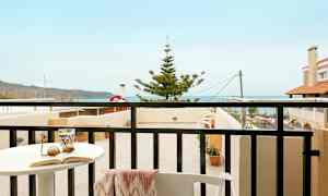 En balkon med udsigt over havet og nærliggende bygninger. (AI-genereret tekst)