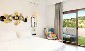 Billede af et hotelværelse med en hvid seng, dekoration på væggen og en dør til en altan. (AI-genereret tekst)