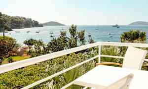 Udsigt fra en altan over havet med både og vegetation. (AI-genereret tekst)