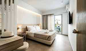 Et hotelværelse med en dobbeltseng, en tv og en balkondør. Skrivebord med hat og stol. (AI-genereret tekst)