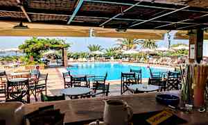 En udendørs serveringsområde med udsigt over en pool og liggestole under parasoller. (AI-genereret tekst)