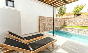 To liggestole ved en lille pool ved siden af en stenmur. (AI-genereret tekst)