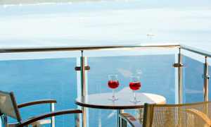 To glas med rød drik på et bord på en altan med udsigt over havet. (AI-genereret tekst)