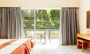 Hotelværelse med to enkeltsenge og stor vinduesdør, der fører ud til en altan. (AI-genereret tekst)