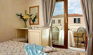 Hotelværelse med udsigt gennem vindue til altan, bord med champagne og udsigt over bygning. (AI-genereret tekst)