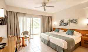 Hotelværelse med to senge, siddeområde og balkon. (AI-genereret tekst)