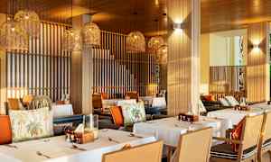 En restaurant med dækkede borde og hængende lampeskærme i flettet design. (AI-genereret tekst)