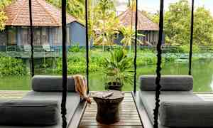 Hængende siddepladser på en terrasse med udsigt over en frodig have og små huse med brune trætage. (AI-genereret tekst)