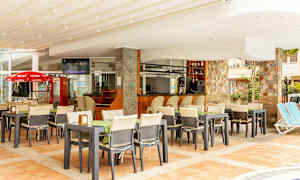 Restaurant med udendørs servering og bar, omgivet af stole og borde. (AI-genereret tekst)