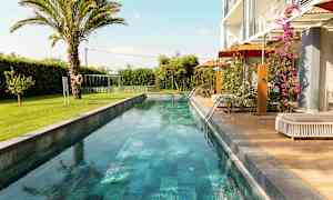 En lang smal pool omgivet af grønne områder og en moderne bolig. (AI-genereret tekst)