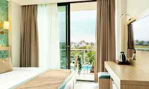 Hotelværelse med altan og udsigt over poolområdet. (AI-genereret tekst)