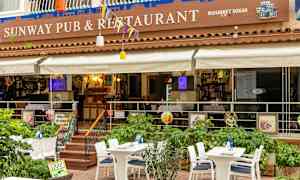 En udendørs terrasse af en restaurant med borde og stole. (AI-genereret tekst)