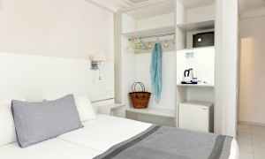 Hotelværelse med seng, garderobe og en minikøleskab. (AI-genereret tekst)