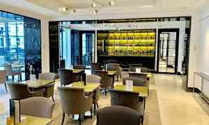 En moderne café med elegante borde og stole samt et veludstyret barspejl i baggrunden. (AI-genereret tekst)