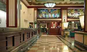 Indgangshal med marmorgulv, receptionsskranke og dekorativt loft. (AI-genereret tekst)