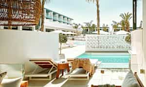 Liggestole ved en swimmingpool med moderne arkitektur i baggrunden. (AI-genereret tekst)