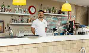 En bar med hylder fyldt med flasker og et ur på væggen. (AI-genereret tekst)