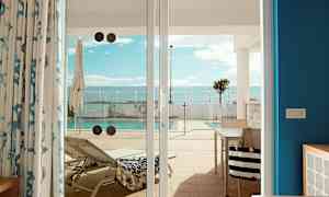 Billede af en liggestol og en pool set fra en terrasse gennem glasdøre. (AI-genereret tekst)