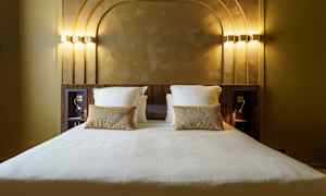 Hotelseng med hvidt sengetøj og guldkast i et rum med dekorativt bagpanel. (AI-genereret tekst)