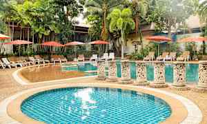 En udendørs swimmingpool omgivet af palmer og liggestole med parasoller. (AI-genereret tekst)