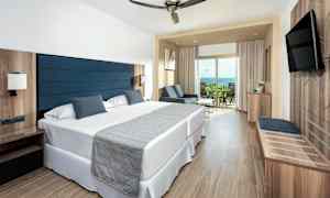 Hotelværelse med to enkeltsenge, siddeområde og balkon. (AI-genereret tekst)